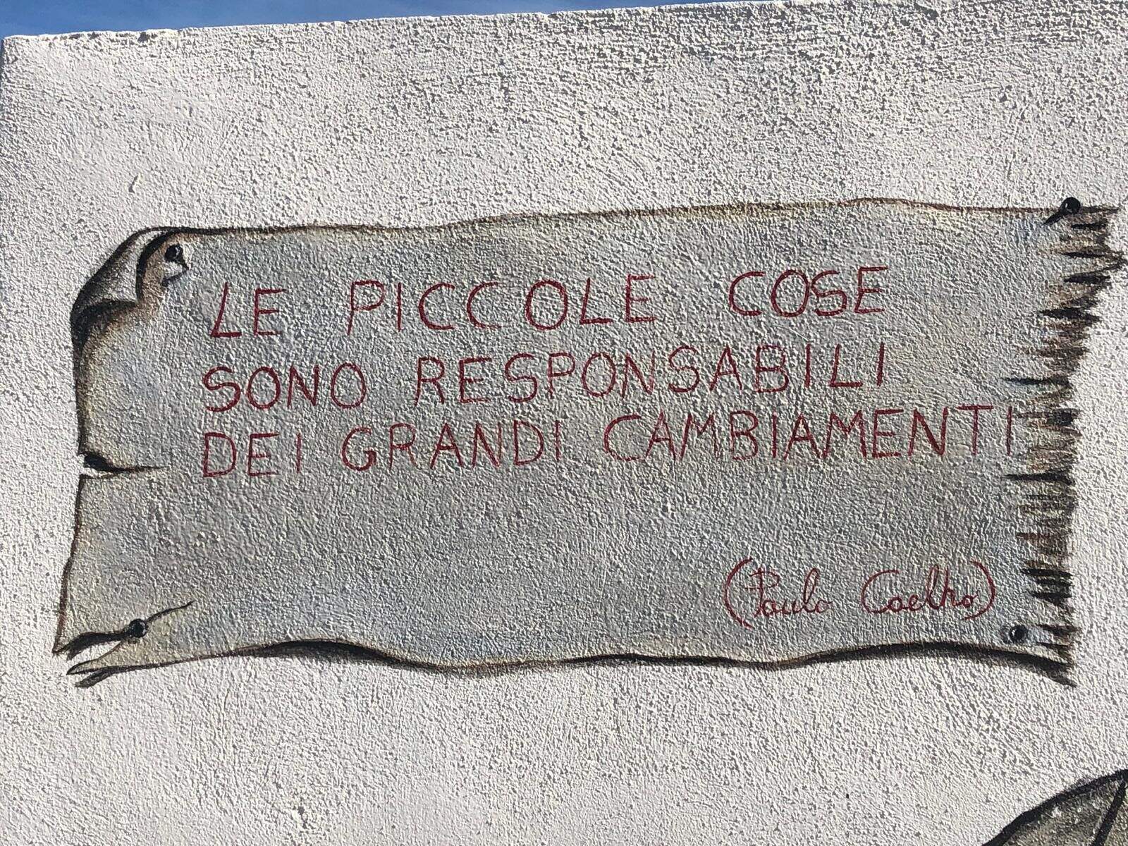 A hand-painted wall reading: small things are responsible for great changes, signed Paulo Coelho