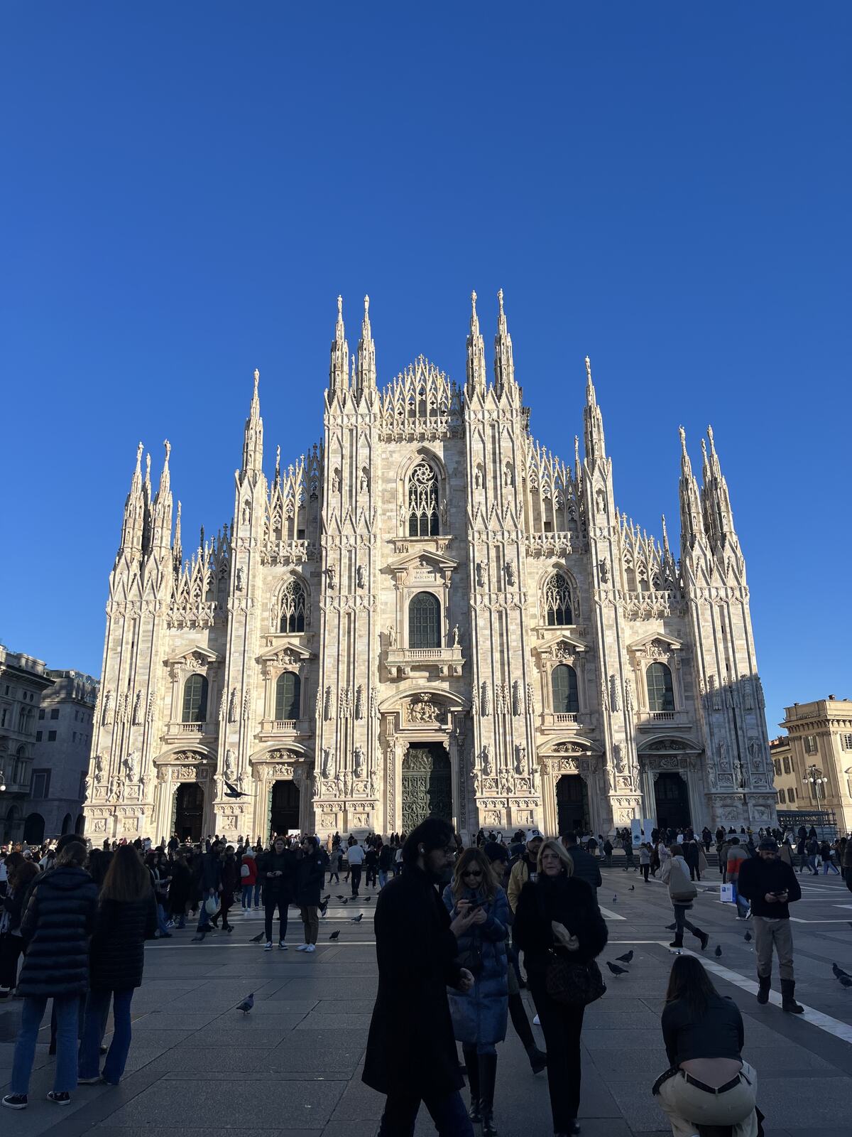The Gothic facade of Milan Cathedral under a blue sky