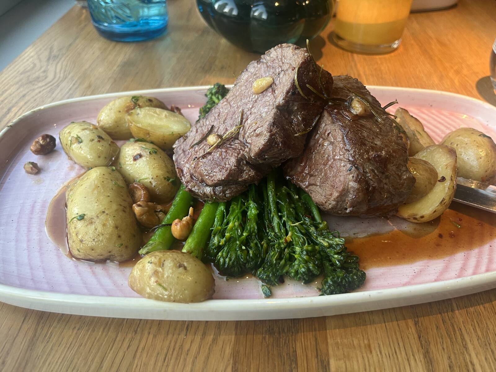 A plate of roasted meat with potatoes and broccolini